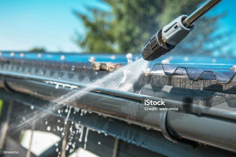 Spring Rain Gutters Cleaning Using Pressure Washer. Closeup Photo.