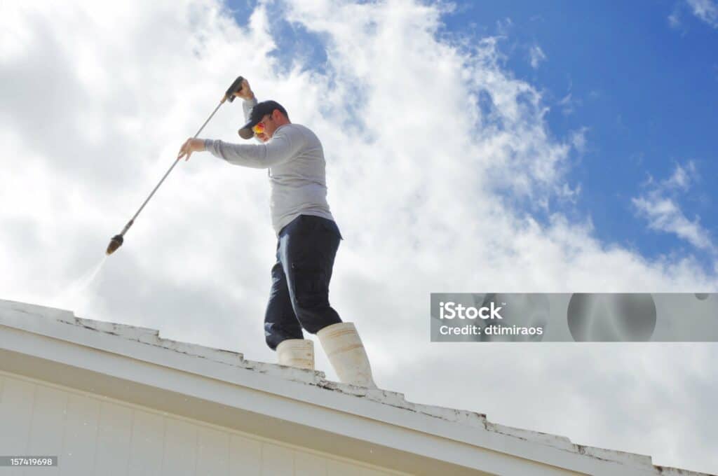 Handy man Pressure cleaning a roof.
